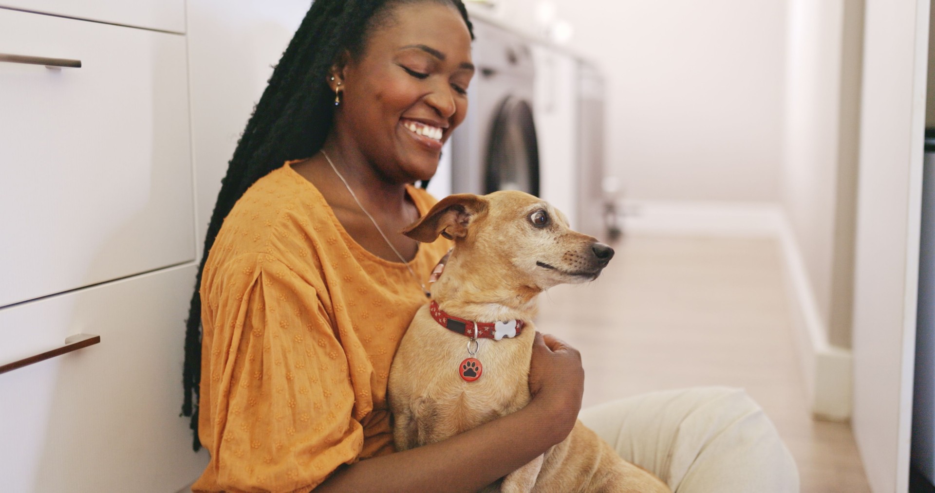 A smiling woman hugging her small dog.